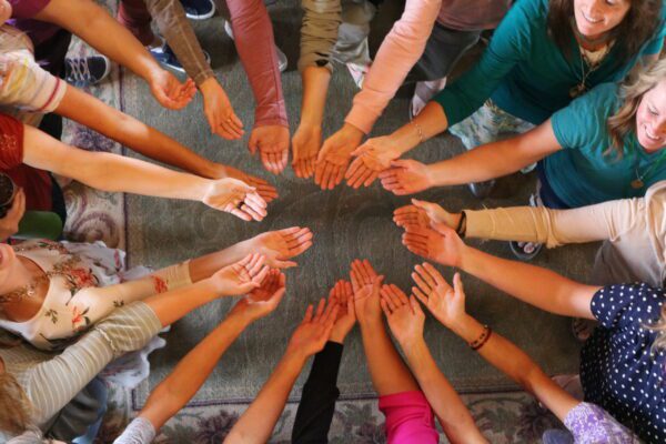 women in circle with hands outstretched in center