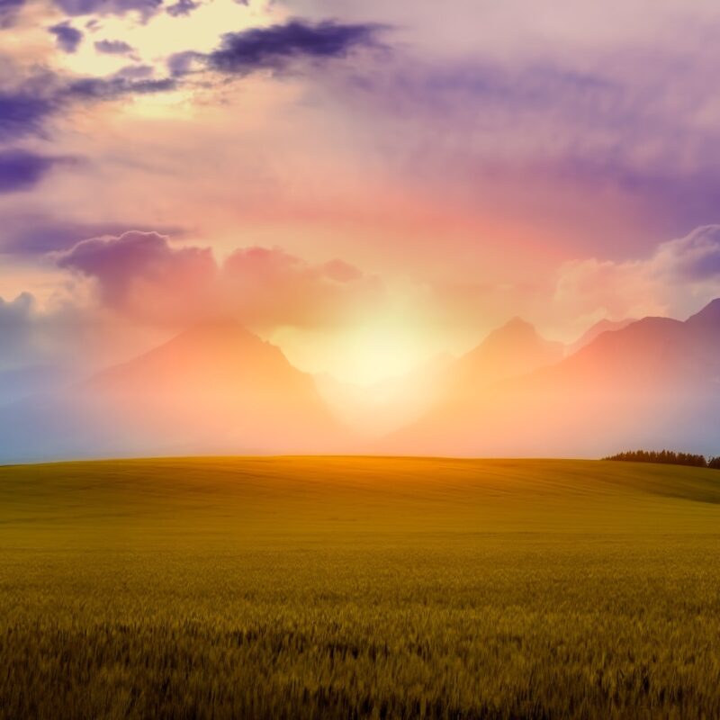 bright, colorful clouds and sun over mountains and rolling hills