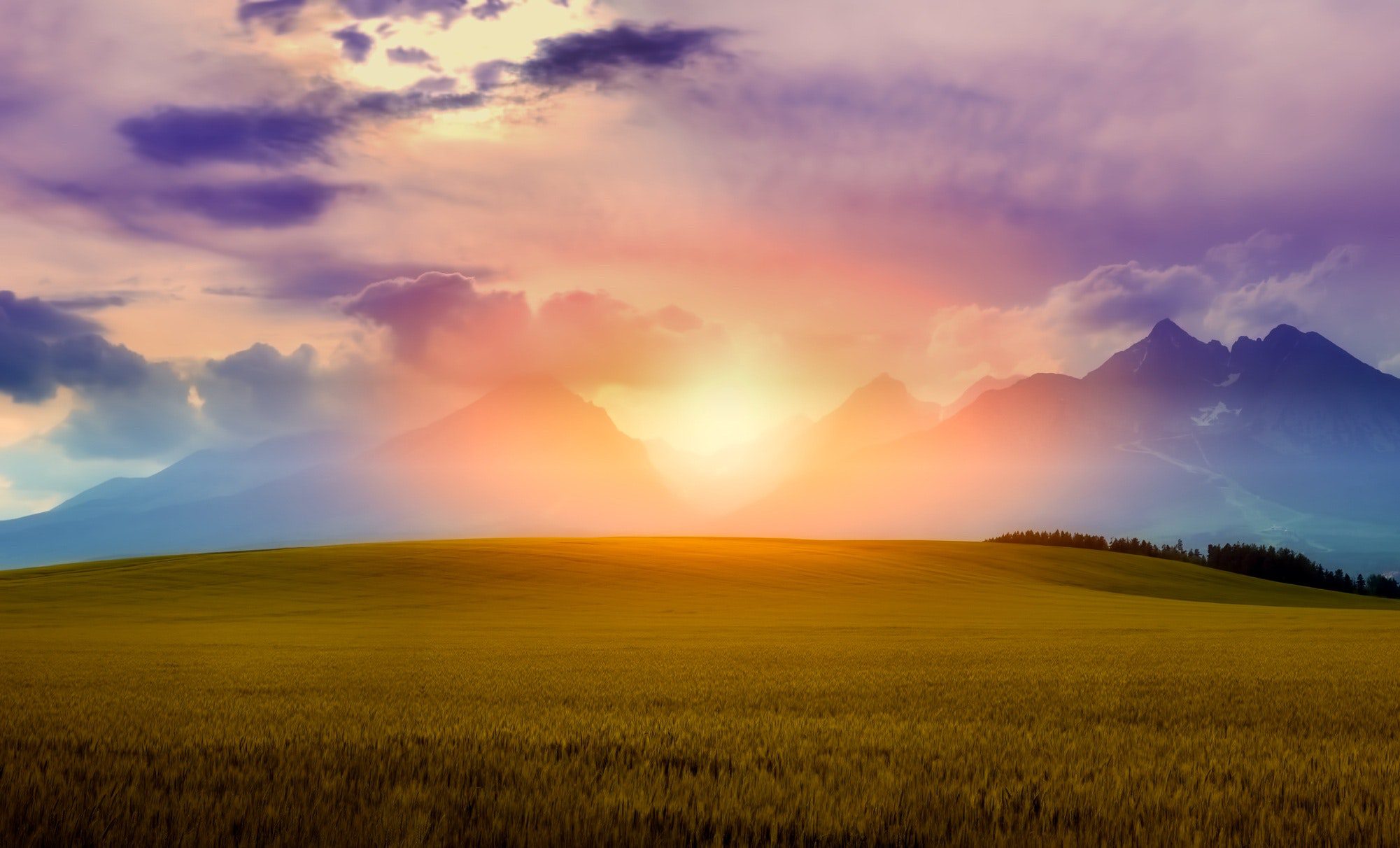 bright, colorful clouds and sun over mountains and rolling hills